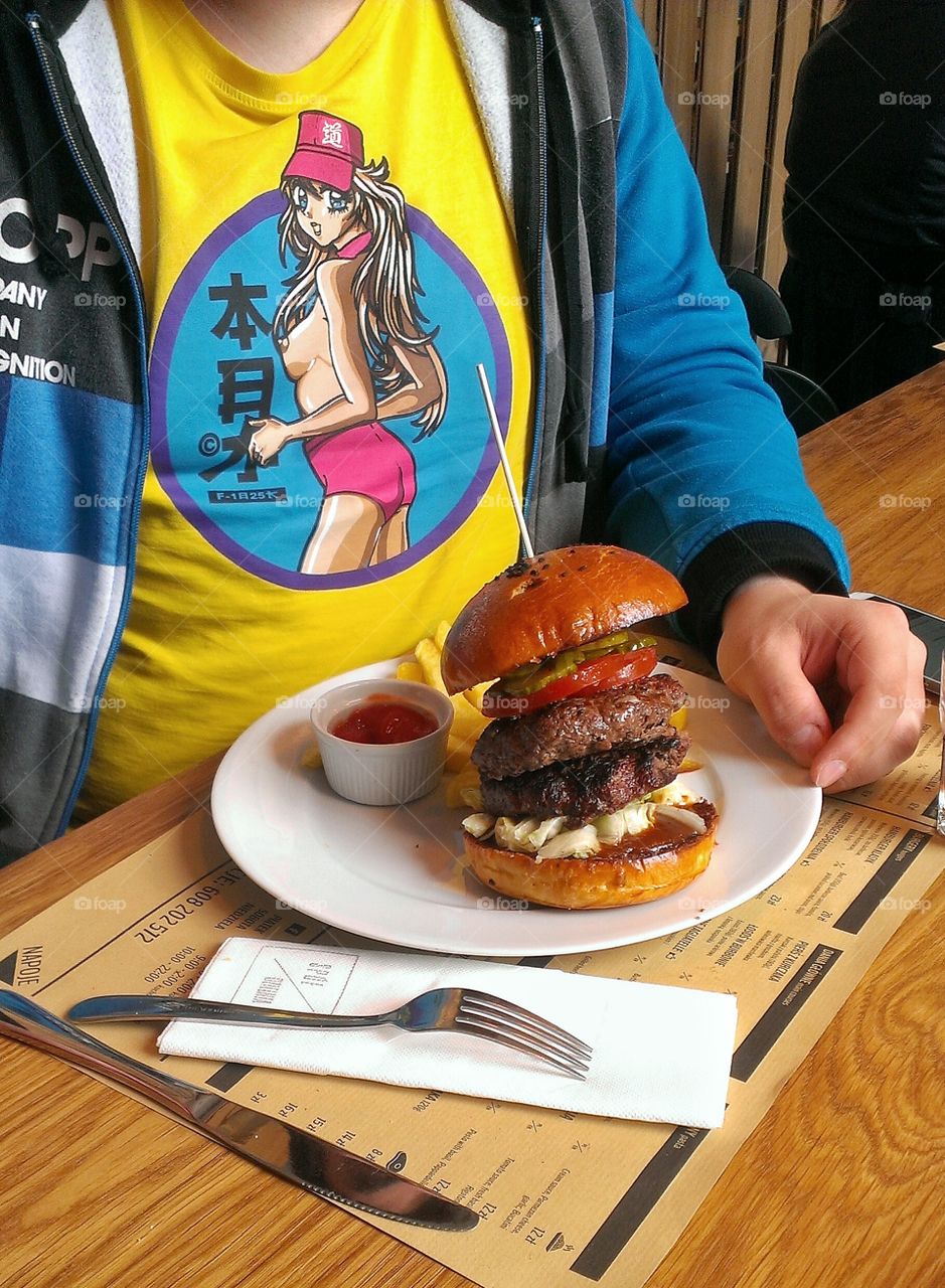 Man sitting in front of burger. Man in funny t-shirt sitting in front of tasty burger