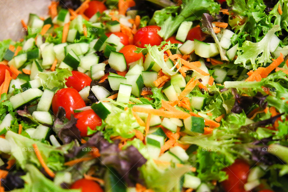 Super healthy organic mix of greens, tomato and cucumbers chopped and made into a colorful salad