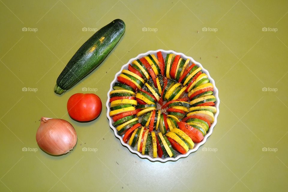 Colorful swirl of a Vegetable Tian of zucchini, yellow squash, tomatoes, onion and garlic and herbs