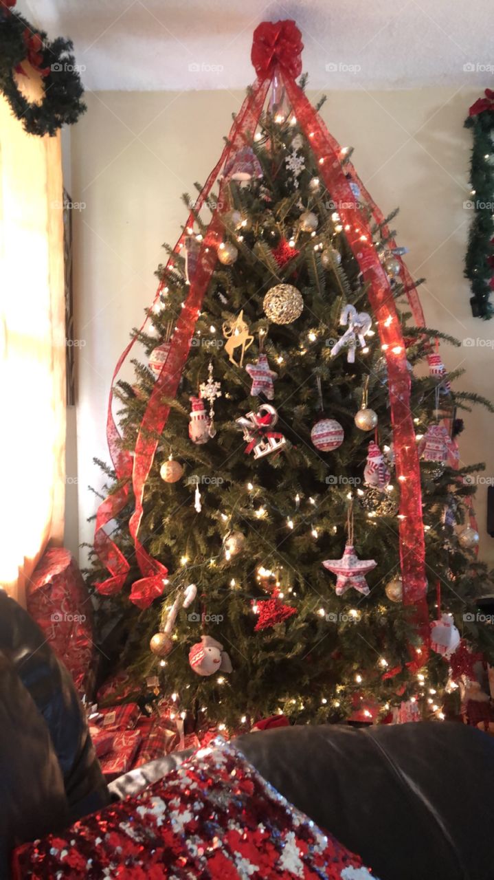 Beautiful Christmas tree with red and  white ornaments and a red topper