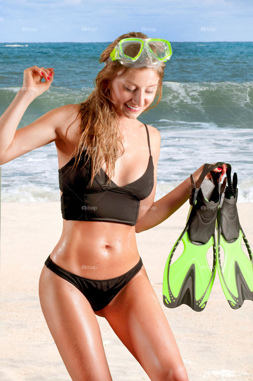Beautiful woman with diving mask and flippers on the beach