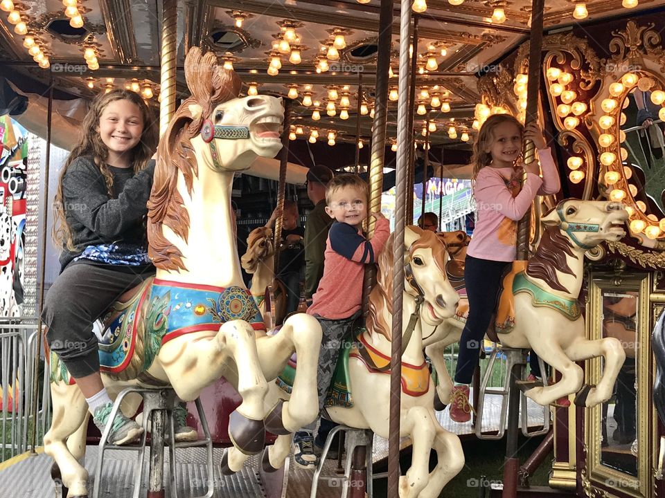 Children's playing in carousel horse at amusement park 