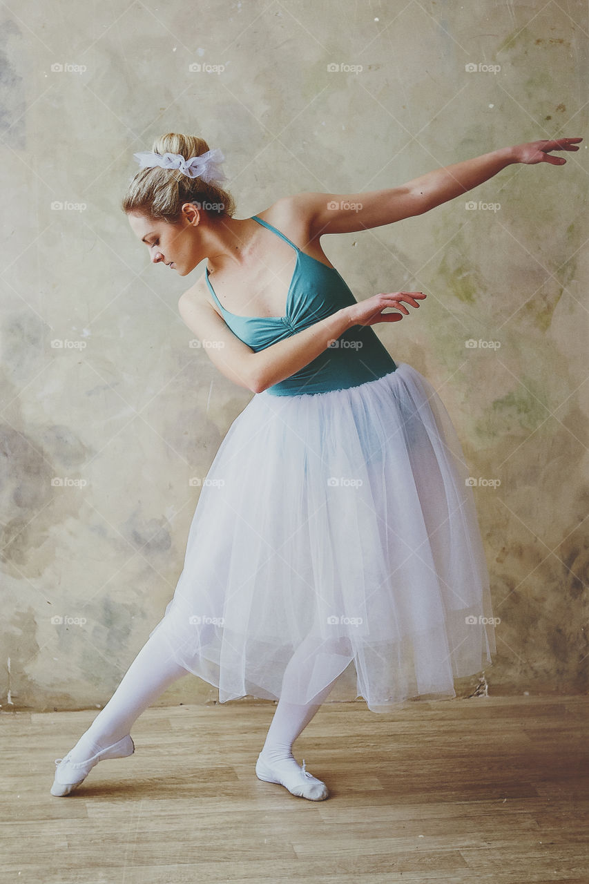 Young and graceful ballerina in pointe shoes and a tutu dances in a studio. Choreography and dancing classes concept. Creative ideas of ballet posing and performance.