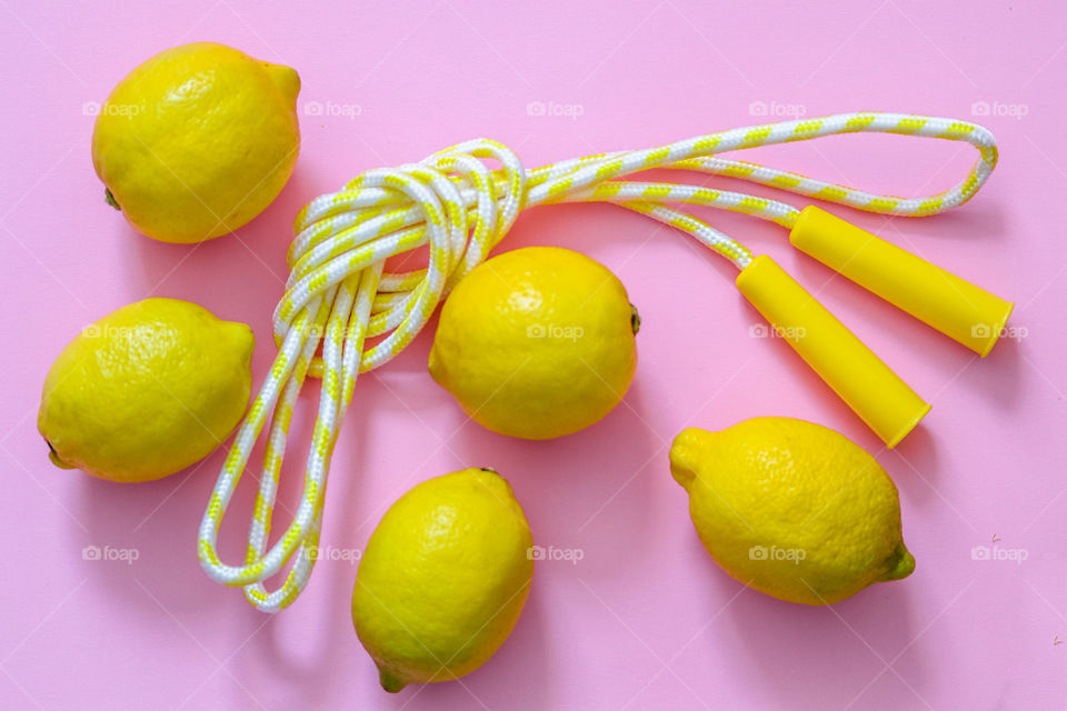Lemons and skipping rope on pink background