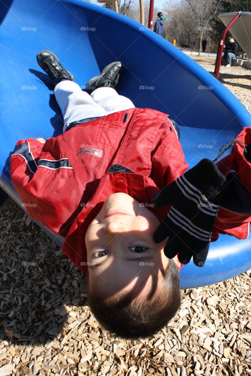 Boy laying upside down on a slide