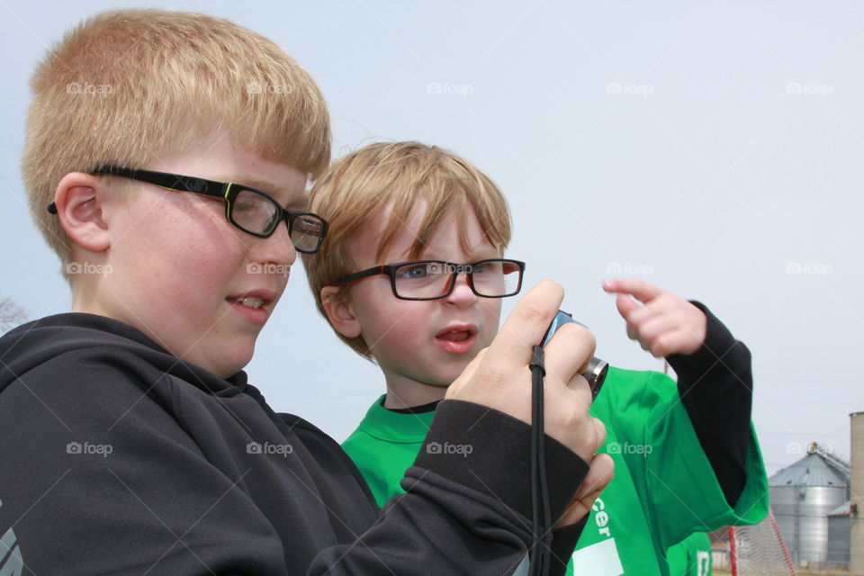 Two young boys in eyes glasses using camera