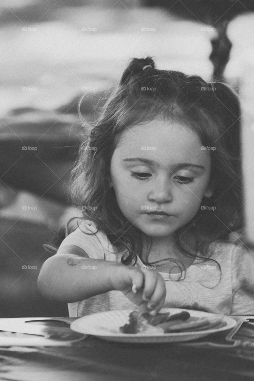 Black and white portrait of a young girl snacking on her 3rd birthday 
