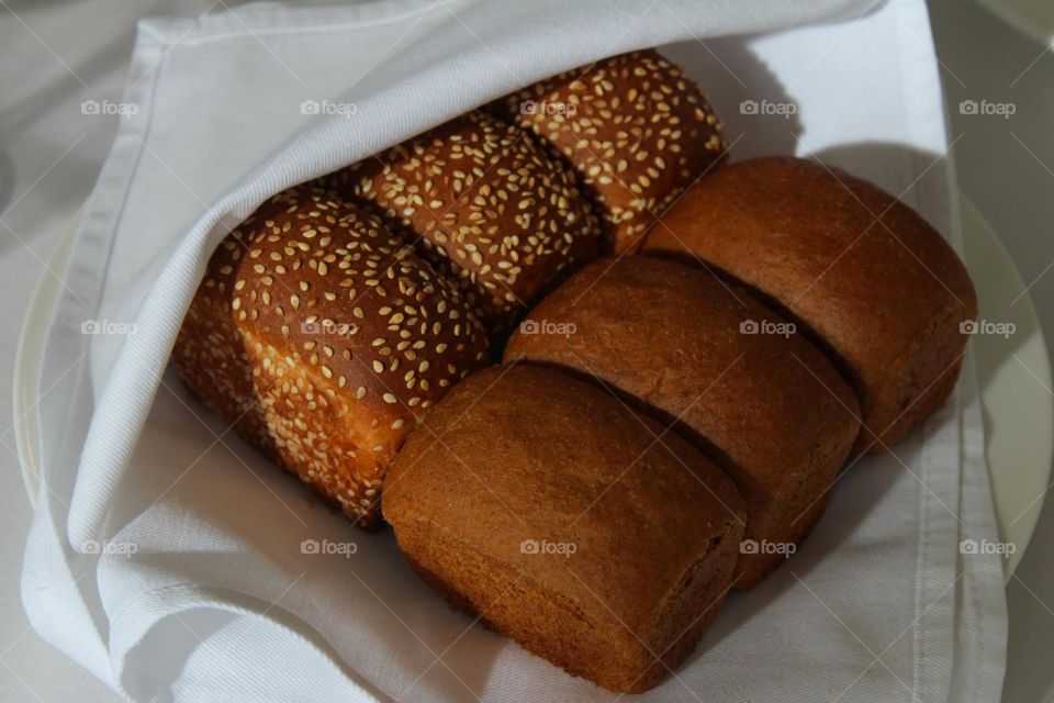 Freshly baked rye bread in a basket with white napkins