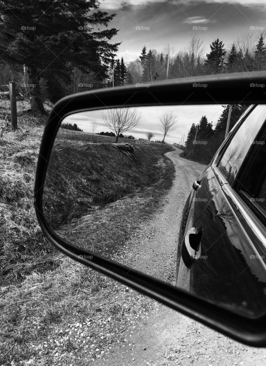 Country dirt road in the rear view mirror. Optical illusion. Black and white. 