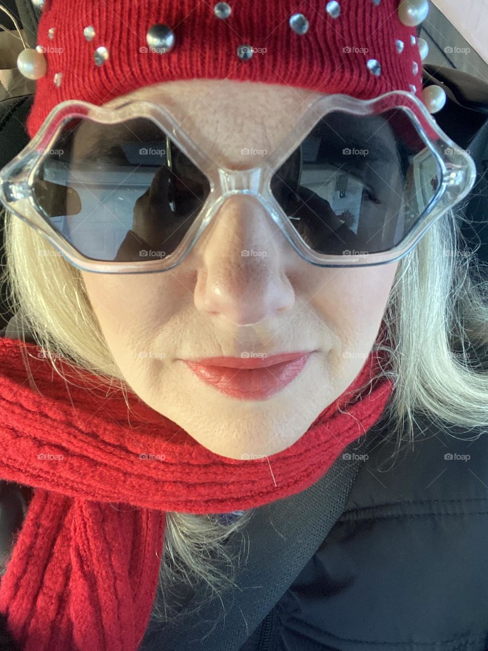 A photo of me wearing a red Christmas hat and scarf given to me by one of my best friends last Christmas, my favorite wavy dollar store sunglasses, and red lipstick. I am powered up in red and ready to start the day!