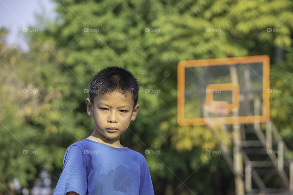 Portrait of Asian boy Sweating face Background on basketball court.