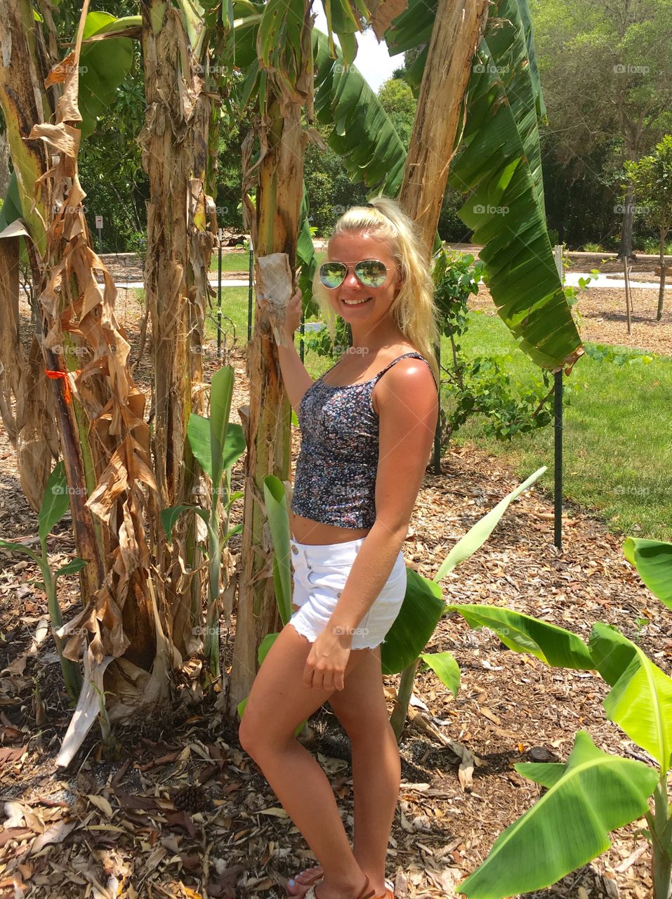 Woman in sunglasses standing near banana plant