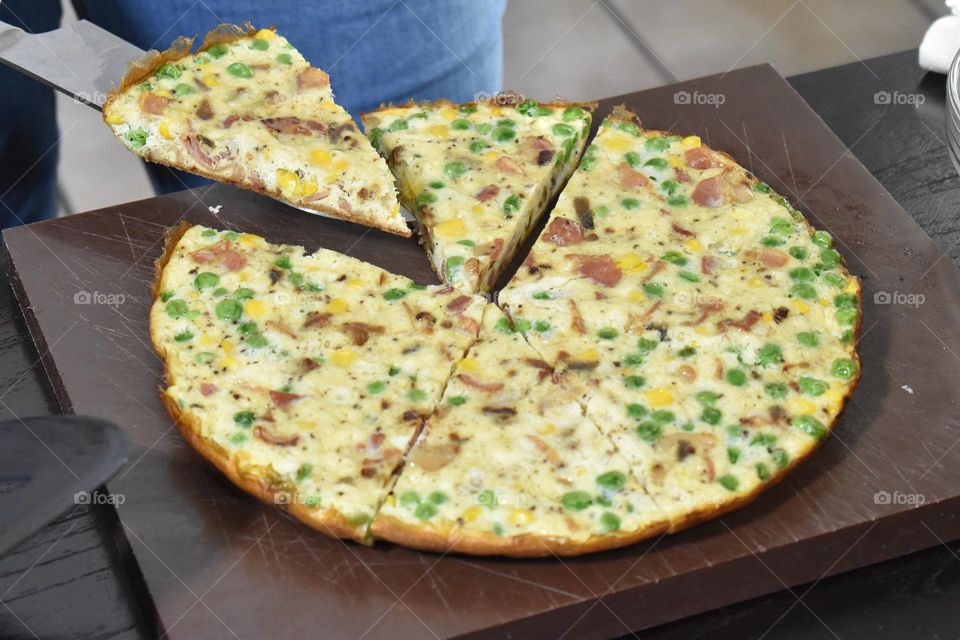 Homecooking cooking Frittata at home and adding and mixing ingredients and removing the Frittata from the pan for cutting and serving on a white plate with tomatoes. Healthy home cooking in kitchen. Breakfast and lunch food preparation. 