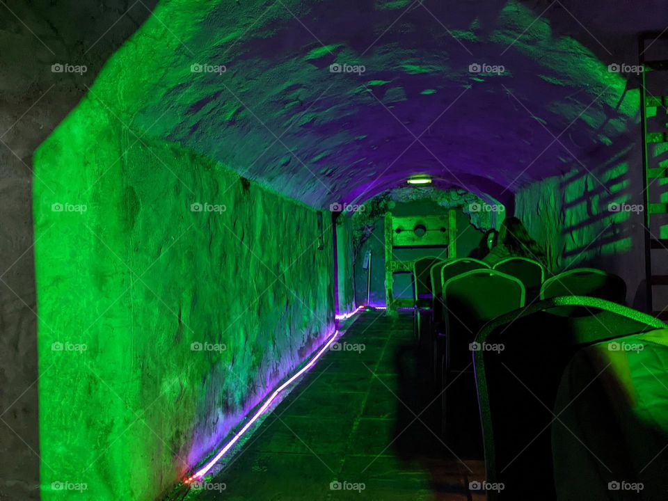 Haunted pubs - ghostly places to drink and socialize in Scotland. Eerie green and purple lighting, stocks in the background, tables along the right of the frame