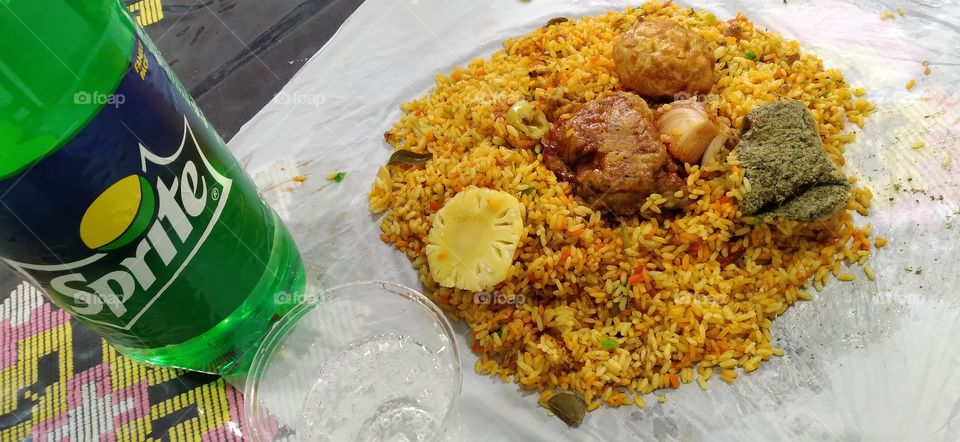 A delicious biriyani with a cup of Sprite.