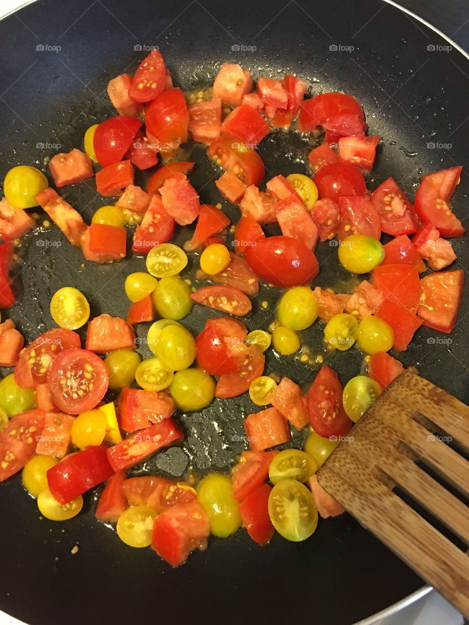Red and yellow tomatoes sautéed in a skillet