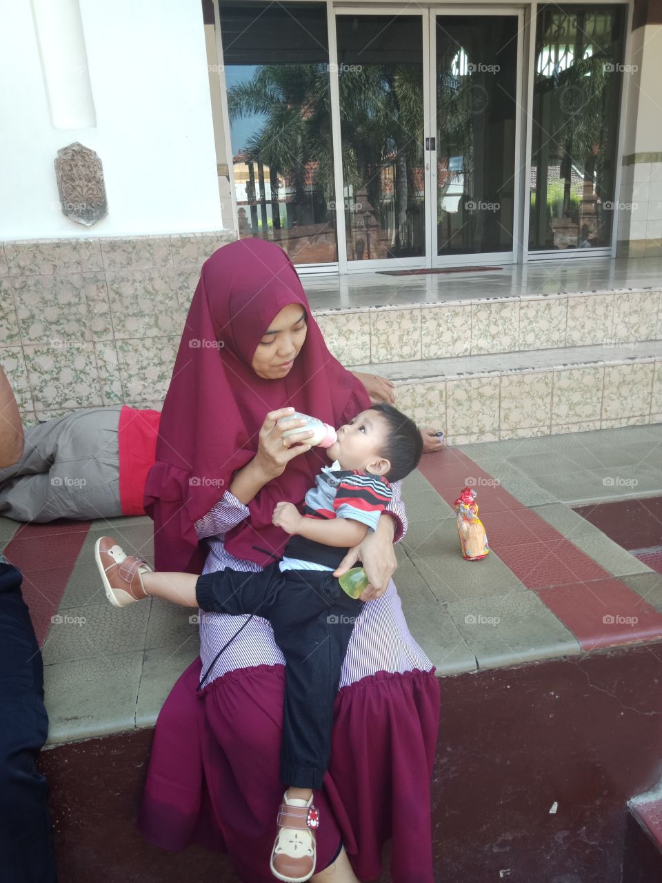 a woman give a bottle of milk to a kid