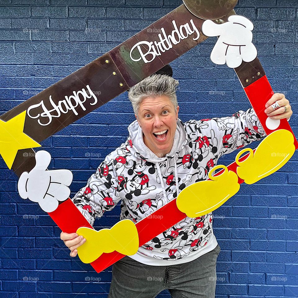 Woman poses with Mickey Mouse for birthday, birthday photo props, having fun on your birthday, birthday shenanigans, fun with the birthday girl 