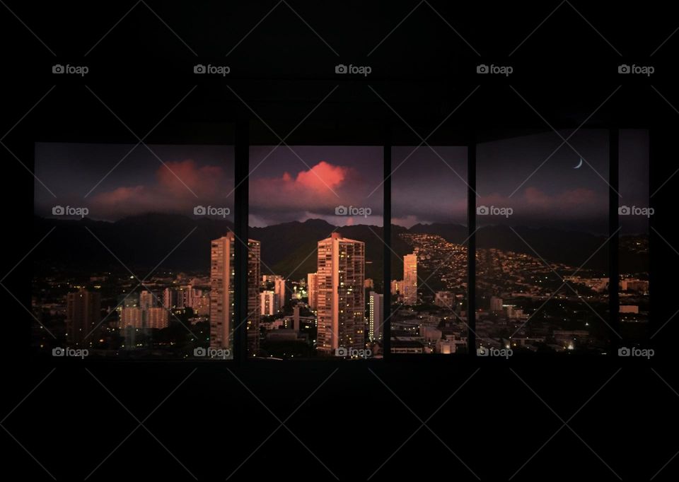 View through window in a darkened room of a Honolulu neighborhood at nightfall 