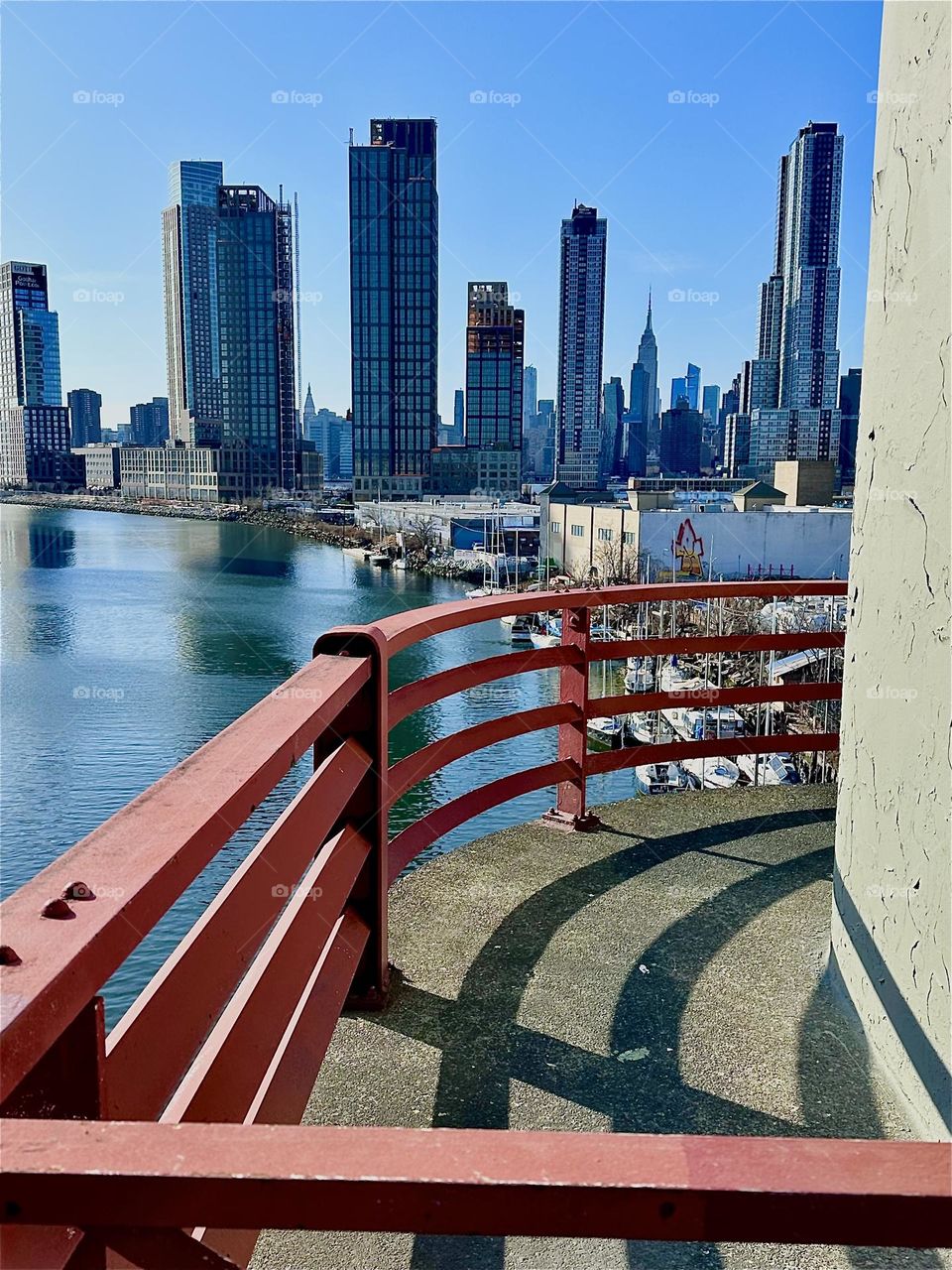 This curvy impression comes to us from the central outpost of the “Pulaski Bridge” at “Newtown Creek” that connects “Greenpoint”, Bklyn and LIC. Straight ahead you see LIC and “Manhattan” incl. the “Empire State Bldg”. 2024. Hypnotic Productions