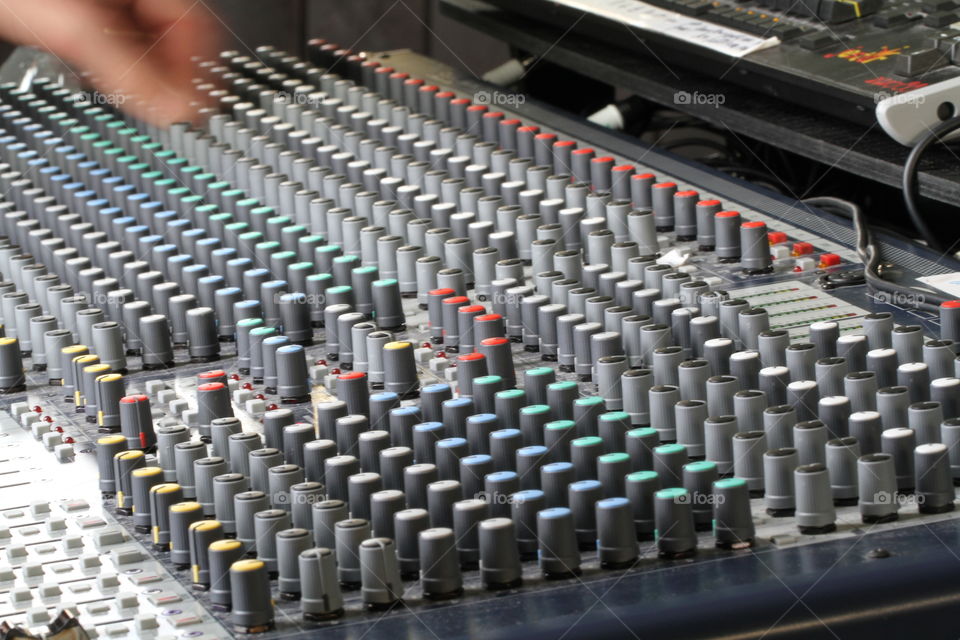 A sound engineer working at a mixing desk at an entertainment venue. The buttons and controls of a dj mixing board or sound desk.