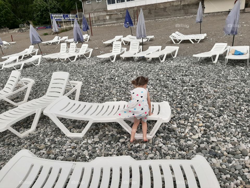 girl in a dress with whate sunbeds on the beach