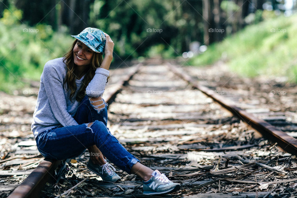 Happy woman sitting on railroad track