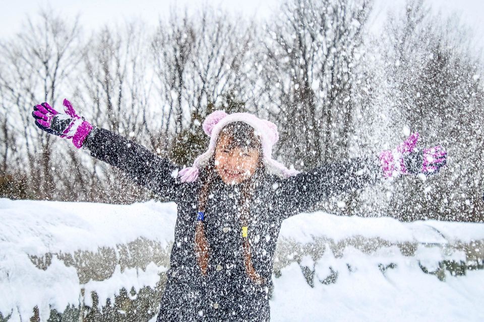 Happy girl is throwing white fresh snow over herself