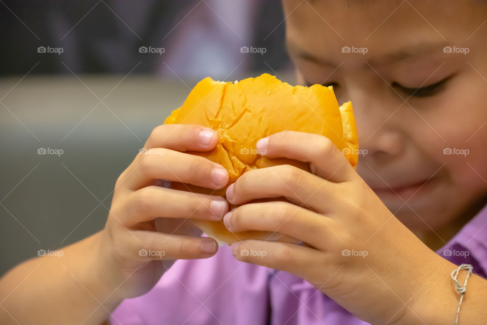 Hamburger fish in hand asia boy holding the eating.