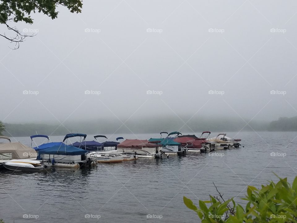 colorful fishing boats docked on lake on foggy morning