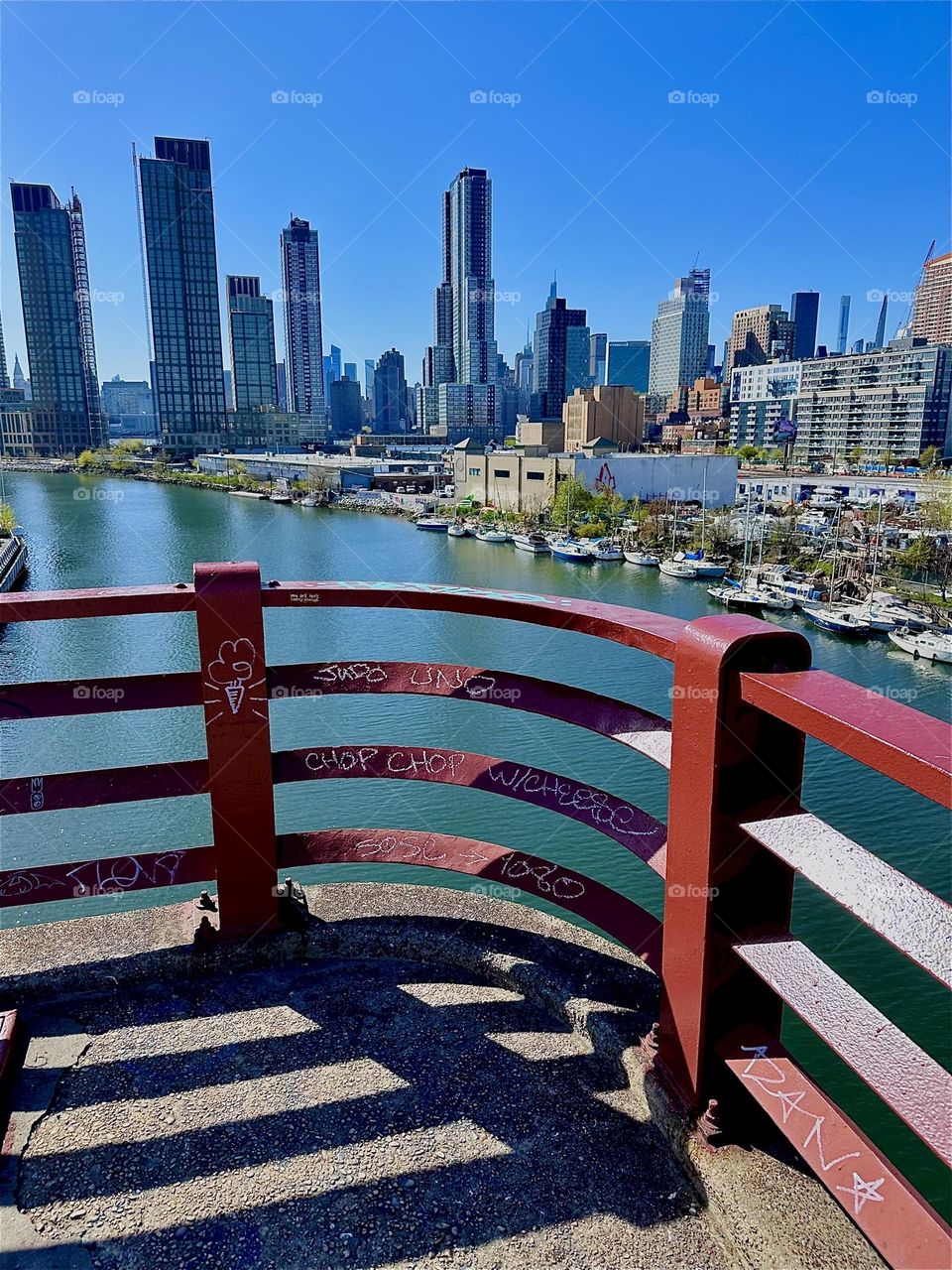 This is “Newtown Creek” seen from the “Pulaski Bridge” that connects “Greenpoint”, Bklyn to LIC, Queens through the grating of the red metal railing. In the distance across the water of the “East River” we see “Manhattan”. 2024. Hypnotic Productions