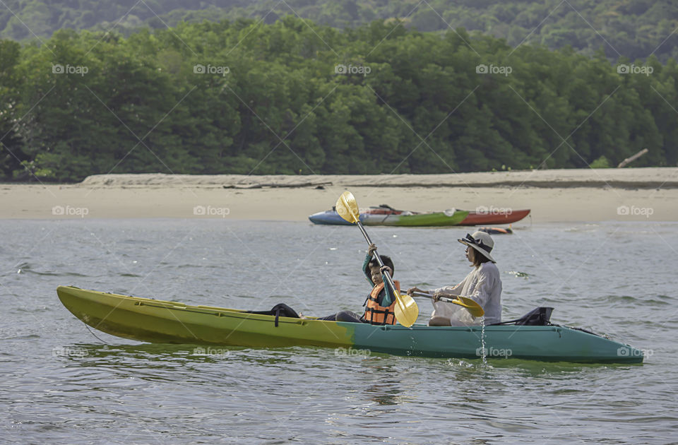 Mother and son kayaking in the sea at Koh Kood, Trat in Thailand.