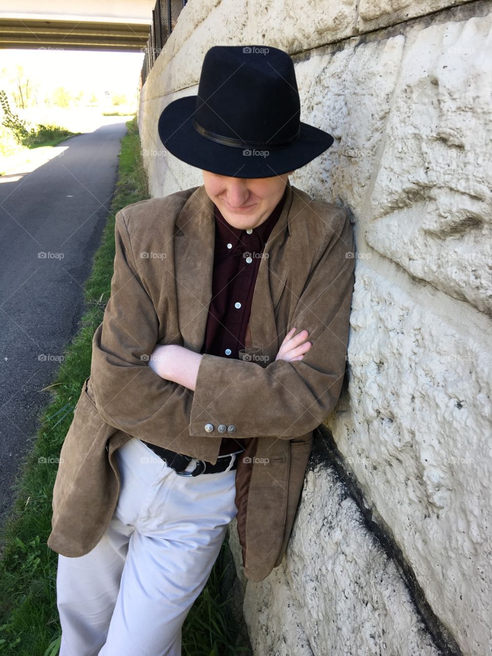 Teenager leaning on wall in hat