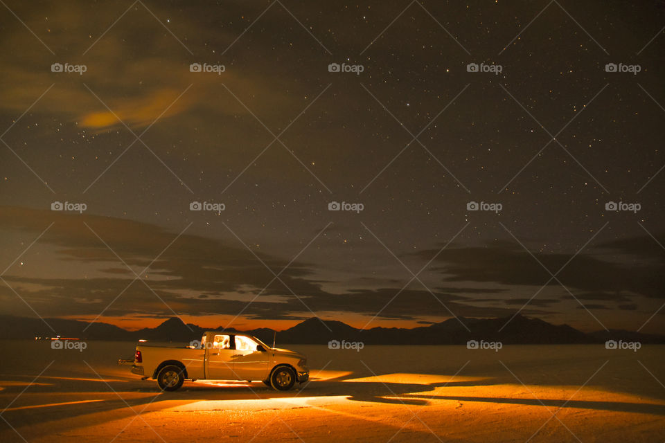 Truck driving through salt flats in USA, stars visible 