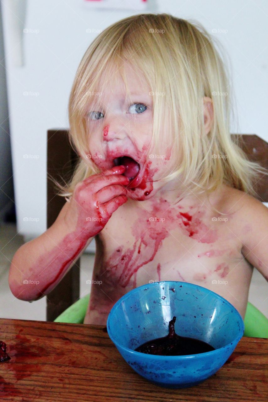 a small child making a big mess while eating blackberries