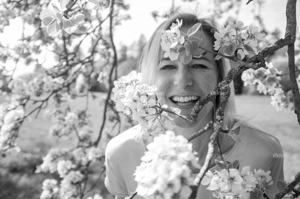 smiling woman between blooming branches of an apple tree - black and white