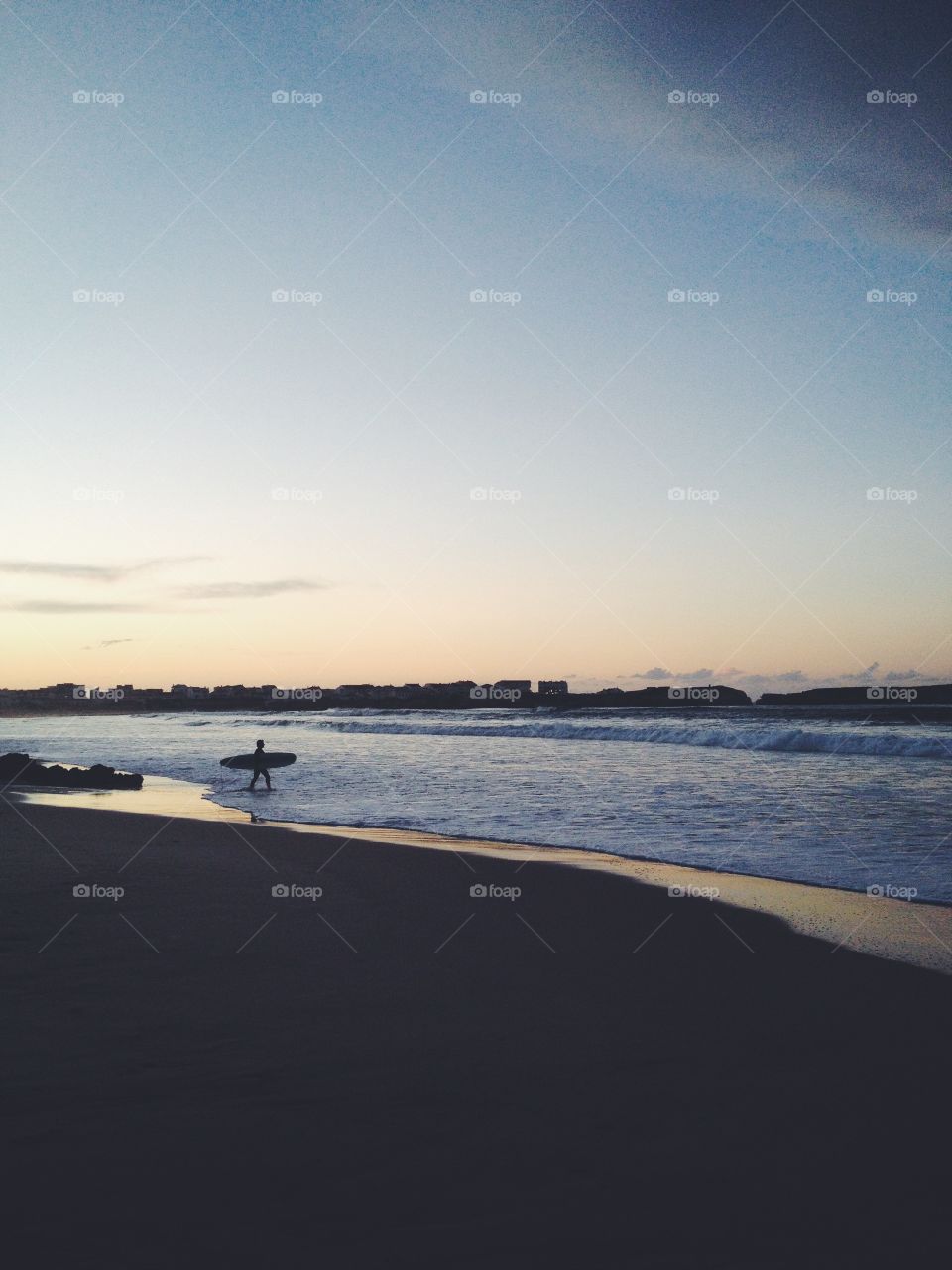 Surfer with surfboard in Peniche. Atlantic Ocean beach.