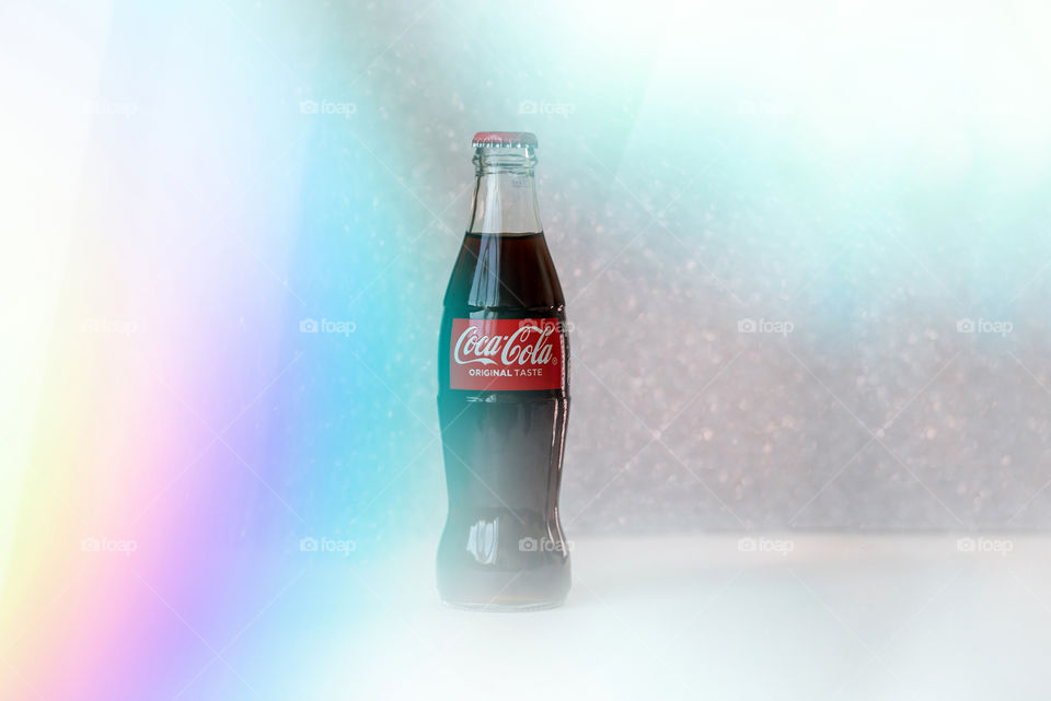 Coca-Cola glass bottle on multicolored background