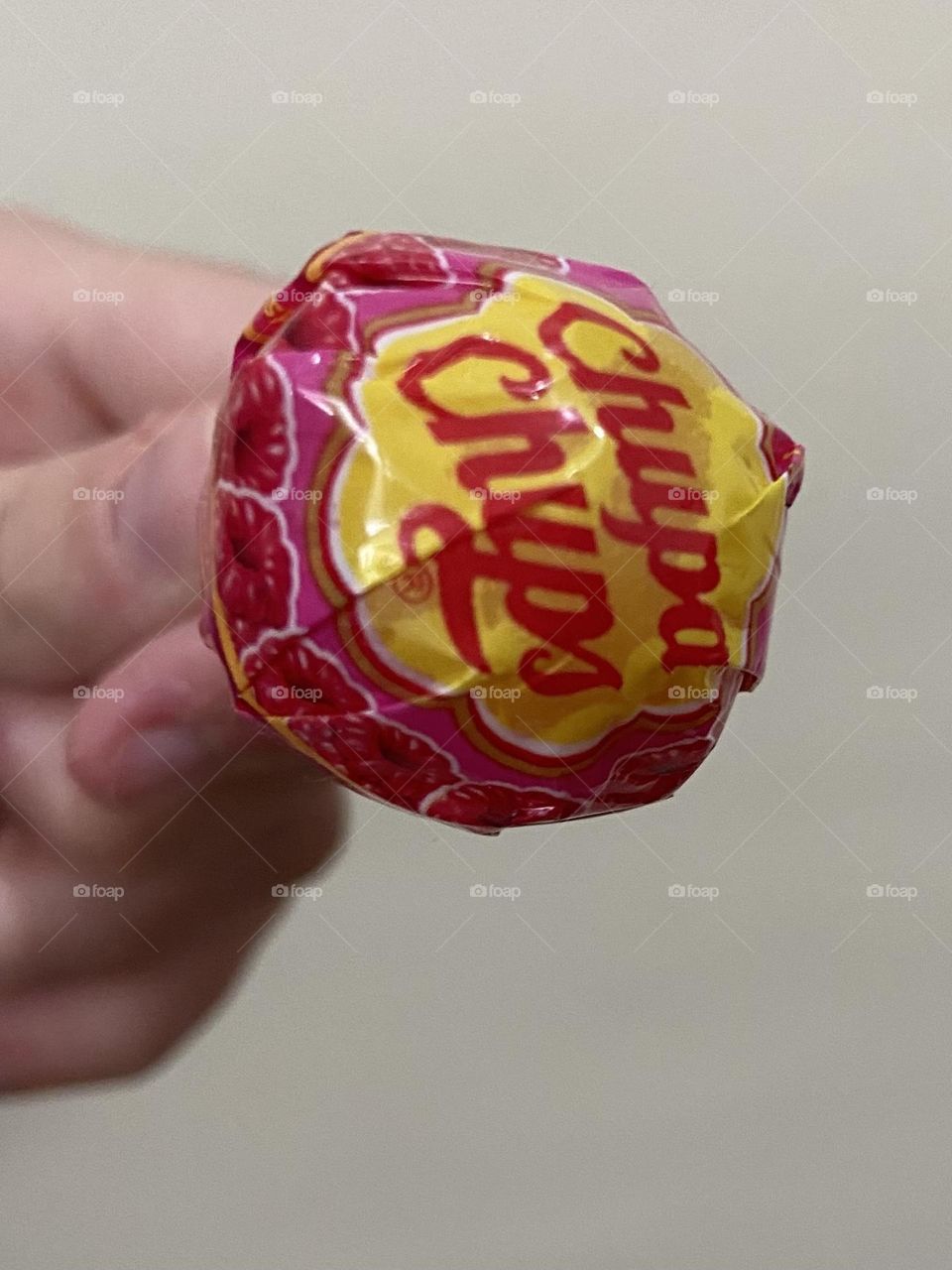 The anticipation of unwrapping of a pink and yellow Chuppa Chups lollipop.
