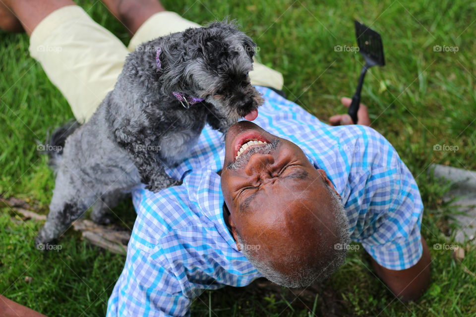Dog licking mature man outdoors