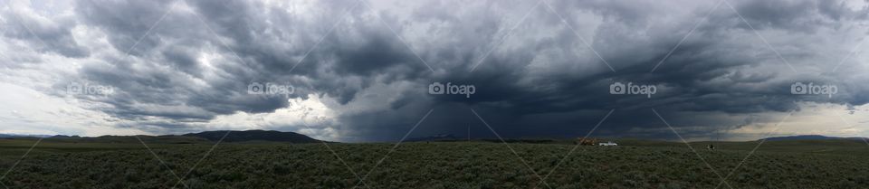 Dark storm cloud over the prairie hills. 