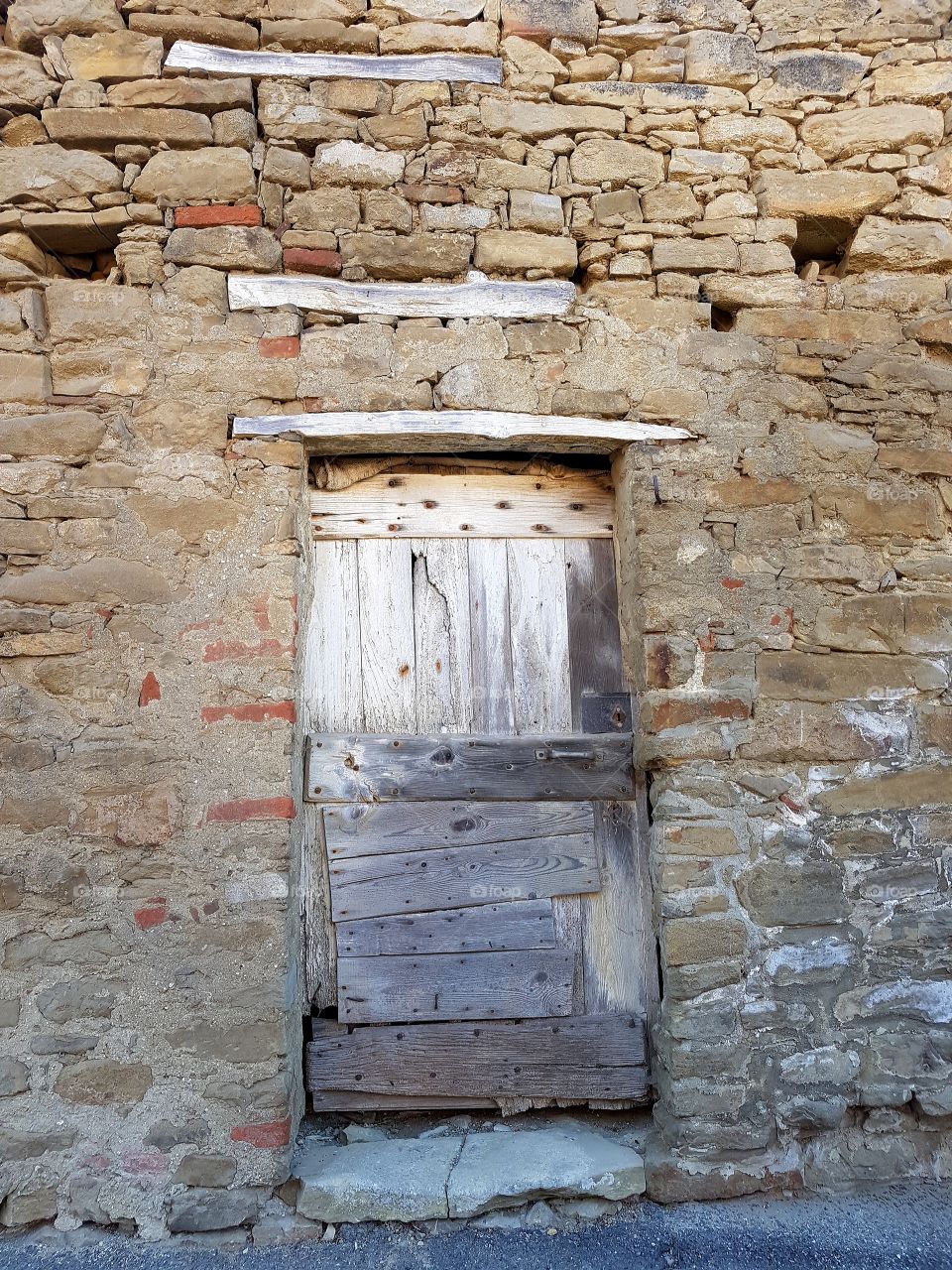 Ancient wood door in a brick and stone wall