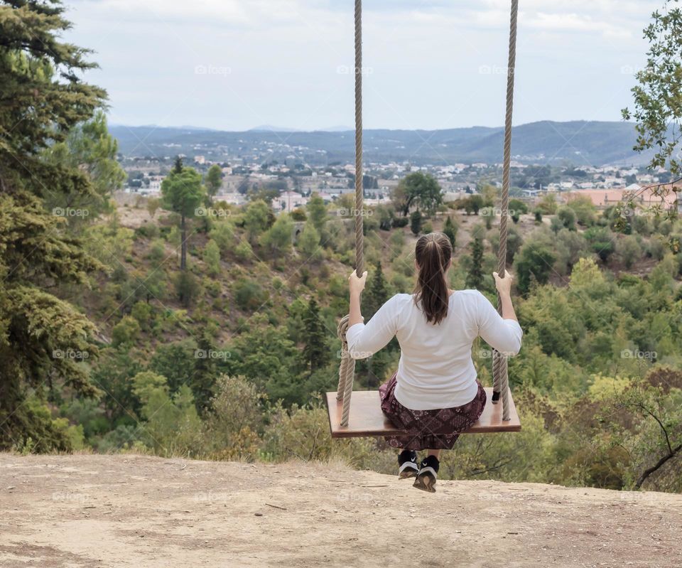 A woman on a swing enjoys the view of 7 Hills National forest and toward Tomar