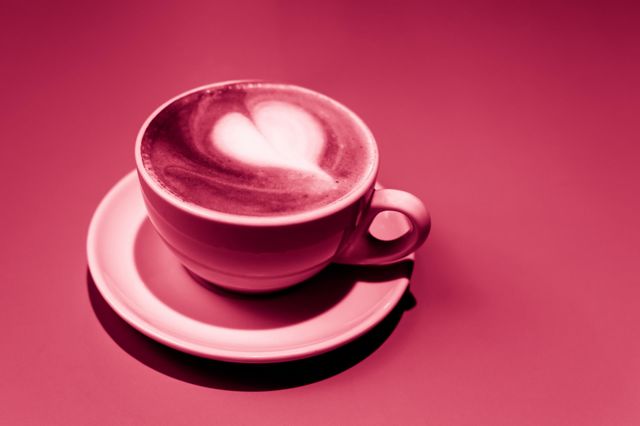 cup of cappuccino with white heart on viva magenta background