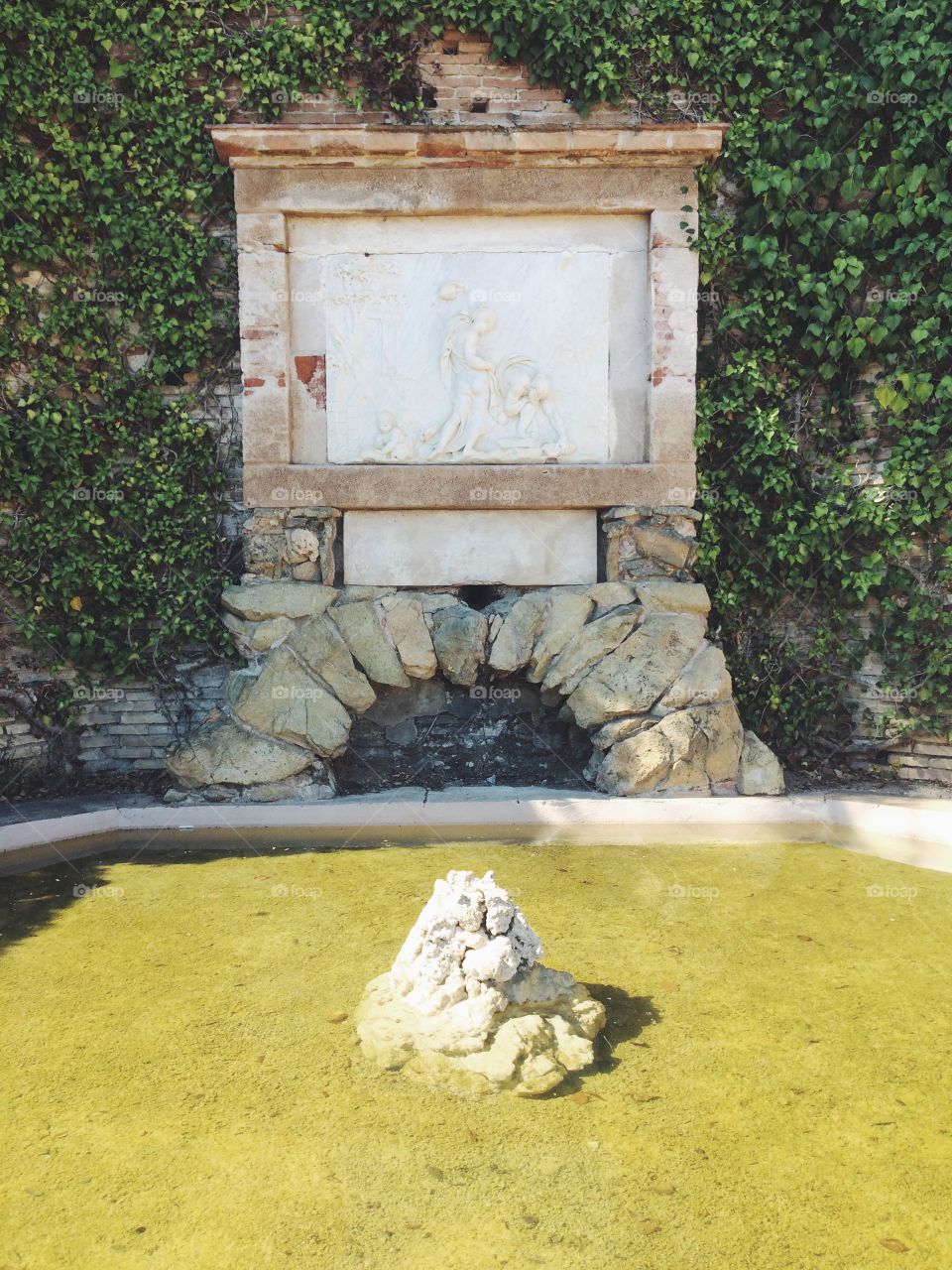 Old fountain on a Sunny day with art at a garden in Barcelona Spain 