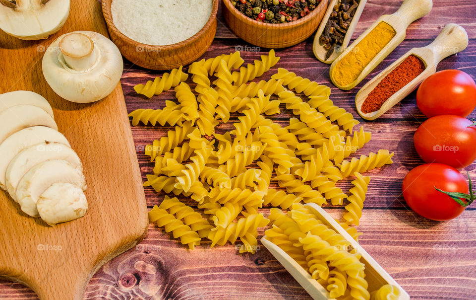 Raw pasta with ingredients and wooden accessories