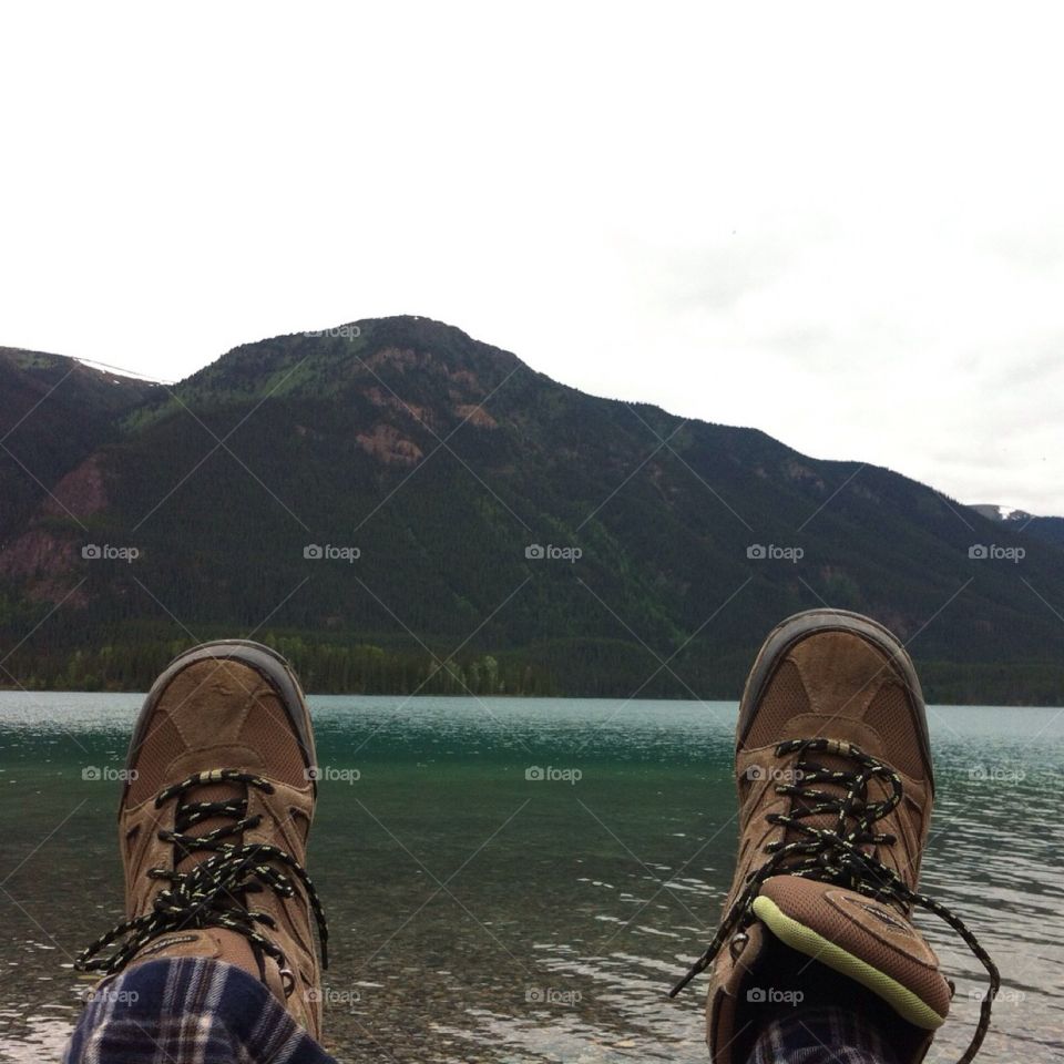 No perfection. Hiking boots resting on log with mountain/lake back ground