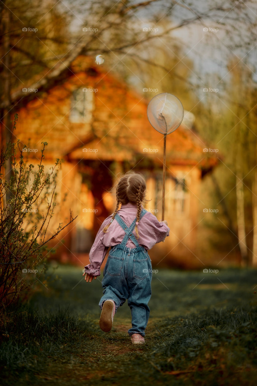 Little girl with butterfly net outdoor at sunset