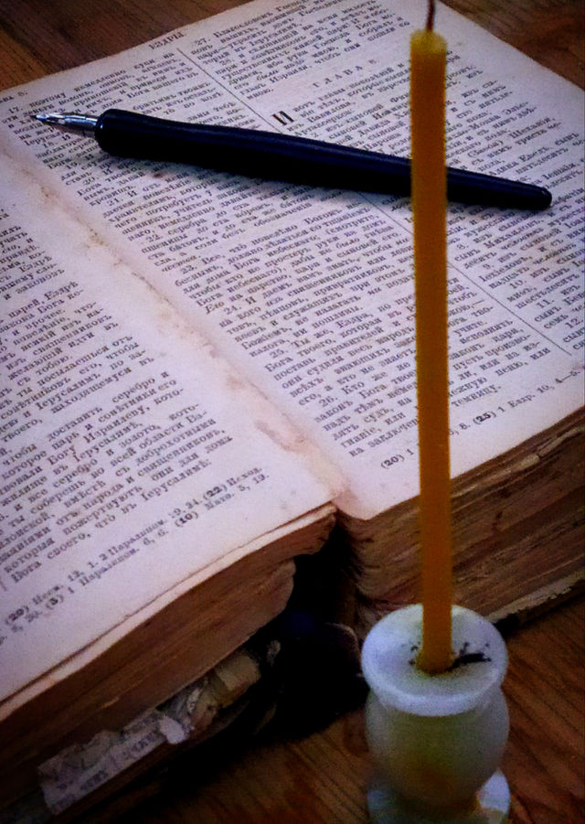 Antique Bible, with quill pen and church candle.  Dusk