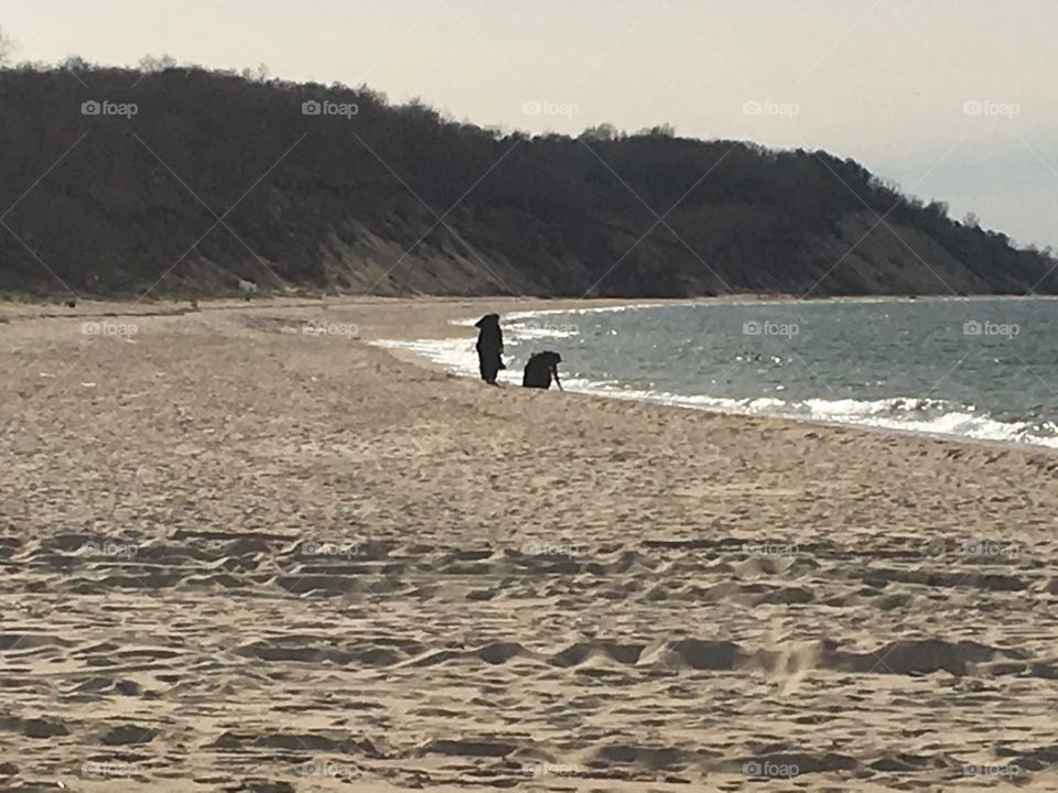 Two nuns walking on the beach near the water gathering seashells.